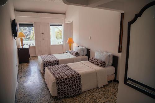 a hotel room with two beds and a window at Hotel Estación by Destino Pacifico in Buenaventura