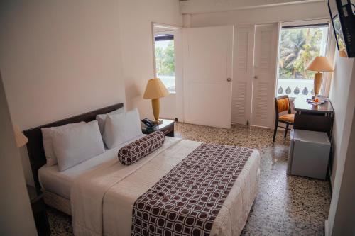 a bedroom with a bed and a desk and a window at Hotel Estación by Destino Pacifico in Buenaventura