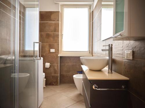 アローナにあるCasa Ierardi - Appartamento Aronaのバスルーム(洗面台、トイレ付)、窓が備わります。