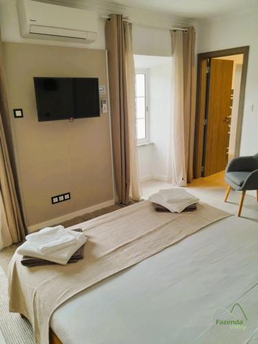 a bedroom with a large bed with a television on the wall at Fazenda Valley in Santa Cruz das Flores