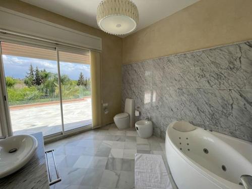 y un baño grande con 2 lavabos, bañera y bañera. en Villa de luxe L'MNAM en Marrakech