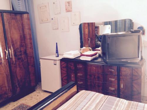 a room with a tv on a dresser with a refrigerator at Stanza Bellaria in Pontedera