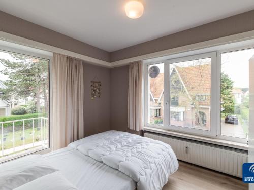 um quarto com uma cama e 2 janelas grandes em Dante 0103 furnished apartment with 2 bedrooms em De Haan