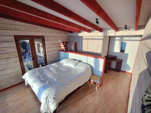 een slaapkamer met een groot bed in een kamer met houten vloeren bij Cabaña Rustica en lagunillas con vista al mar in Navidad