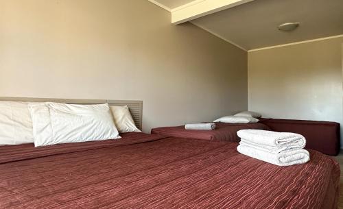 two beds in a hotel room with towels on them at The Crossing Lodge & Backpackers in Erua