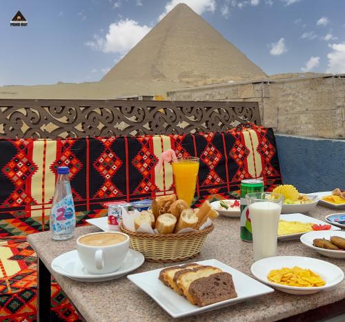 una mesa con platos de comida y una pirámide en Pyramids Height Hotel & Pyramids Master Scene Rooftop en El Cairo