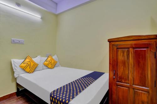 a bedroom with a bed and a wooden cabinet at SPOT ON 81230 J Square in Trivandrum