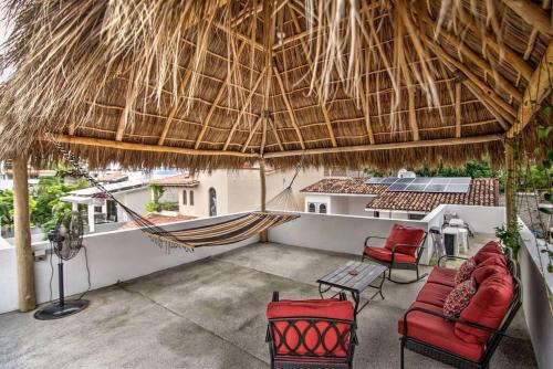 a patio with red chairs and a thatched roof at Las Vueltas - Golden Zone Studio 2 Blocks to Beach in Bucerías
