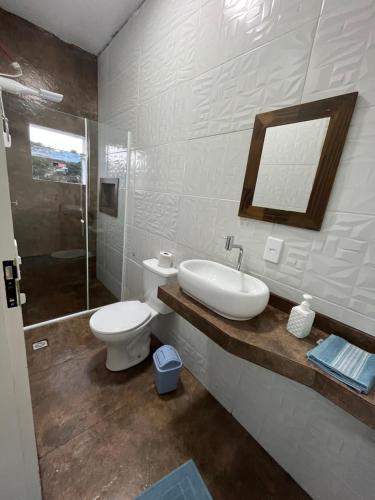 La salle de bains est pourvue d'un lavabo, de toilettes et d'un miroir. dans l'établissement Hotel Cidade Paisagem, à Piquete