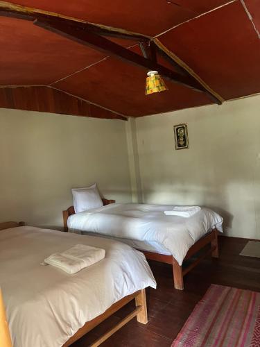 two beds in a room with white sheets at Refugio de Mery Lucmabamba in Sahuayacu