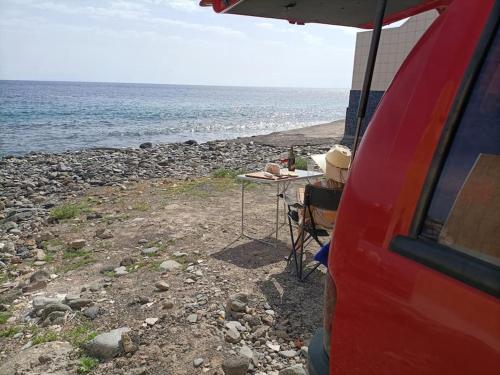 a table and chair on a rocky beach next to the ocean at w DiscoveryCanarias II in San Miguel de Abona