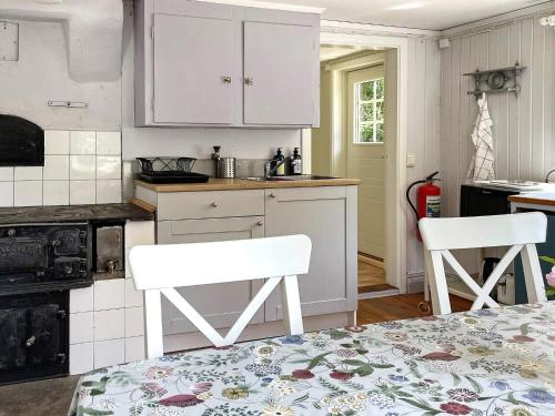 a kitchen with white cabinets and two white chairs at 5 person holiday home in VALDEMARSVIK-By Traum in Valdemarsvik