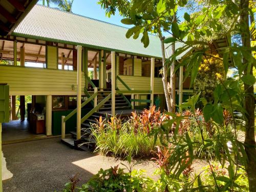 a green building with a porch and some plants at Jackaroo Treehouse Rainforest Retreat in Mission Beach