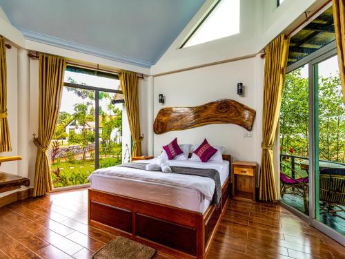 a bedroom with a bed with a large wooden headboard at LA PETITE MANGROVE Resort in Phumĭ Srângam