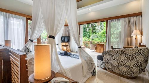 a bedroom with a bed and a chair and a window at KajaNe Mua at Ubud Bali in Ubud