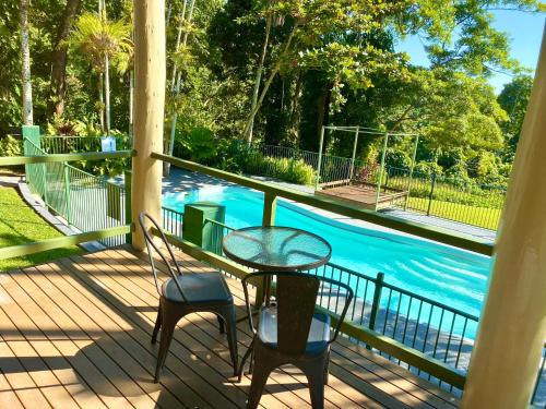 a patio with a table and chairs next to a pool at Jackaroo Treehouse Rainforest Retreat in Mission Beach