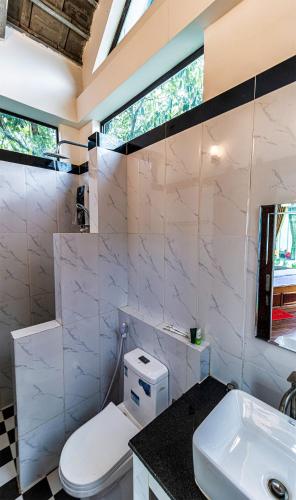 a white bathroom with a toilet and a sink at LA PETITE MANGROVE Resort in Phumĭ Srângam