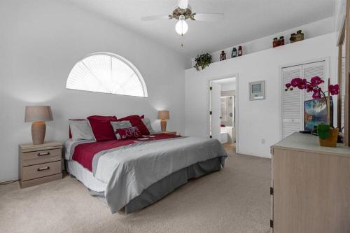 a bedroom with a bed with red pillows and a window at 2974 Viscount Villa 3bed+ Pool&Spa in Kissimmee