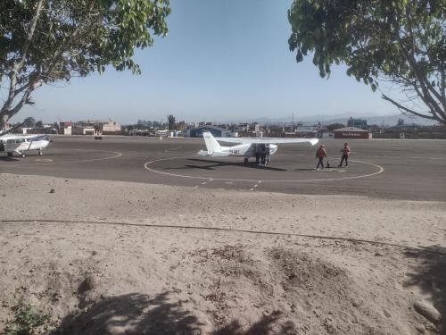 a small plane on a runway with people walking around it at 420 Route's Backpackers in Nazca