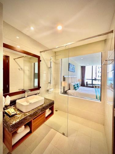 a bathroom with a sink and a mirror and a bed at Avatar Danang Hotel in Da Nang