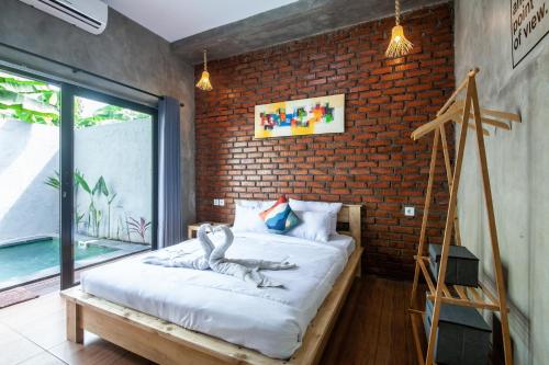 Cama en habitación con pared de ladrillo en The Backyard Villas en Tabanan