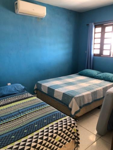 Paraíso dos Oliveira في ساو جوزيه دا كوروا غراندي: سريرين في غرفة بجدران زرقاء ونافذة