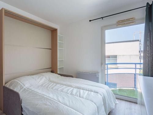 une chambre avec un lit blanc et une grande fenêtre dans l'établissement Studio refait à neuf à Anglet, proche commerces & plages, avec balcon et parking gratuit - FR-1-3-594, à Anglet