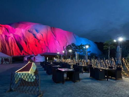 a group of tables and chairs in front of a mountain at night at KaoShan Tent Zhangye in Zhangye