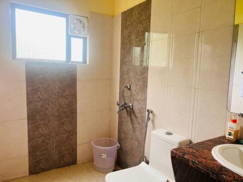 een badkamer met een douche, een toilet en een wastafel bij The HeartWood Farms Inn in Rāmnagar