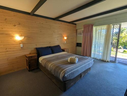 1 dormitorio con 1 cama grande y pared de madera en Gloucester Motel Pemberton Manjimup, en Pemberton