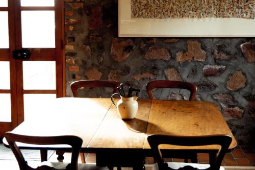 einem Holztisch mit Stühlen und einer Vase darauf in der Unterkunft The Blacksmith's Cottage at Lisdillon Vineyard in Little Swanport