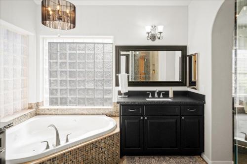 a bathroom with a tub and a sink and a mirror at Scottsdale Escape - Pool, Spa, Firepit, & Pool Table in Phoenix