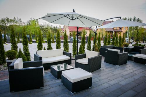a patio with couches and tables and an umbrella at Pensjonat & Spa Raj in Rajgród