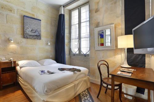 Dormitorio con cama, escritorio y TV en Hôtel La Tour Intendance, en Burdeos