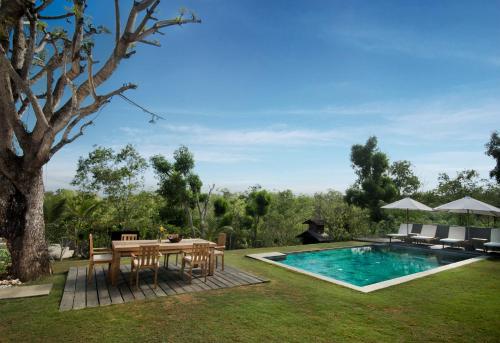 a backyard with a table and chairs and a pool at RUMAH WAYAN ULUWATU in Uluwatu