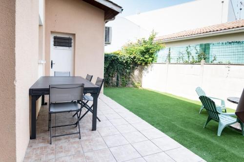 patio con tavolo e sedie su un prato di Maison de Larros, au calme idéalement placée a Gujan-Mestras