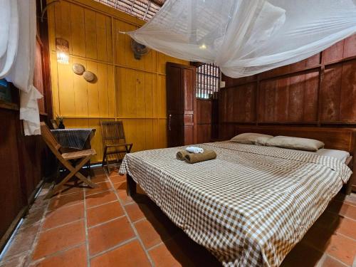 a bedroom with a bed and a chair in it at Ba Danh Homestay & Kitchen - Ben Tre Mekong in Ben Tre