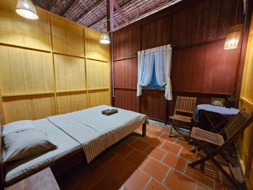 a bedroom with a bed and a chair in it at Ba Danh Homestay & Kitchen - Ben Tre Mekong in Ben Tre