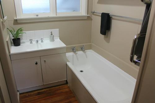 baño blanco con lavabo y ventana en Bauchops Hill Station Farmstay, en Burkes Pass