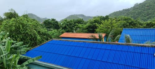 a building with blue roofs with mountains in the background at Khmer House Guesthouse in Kep