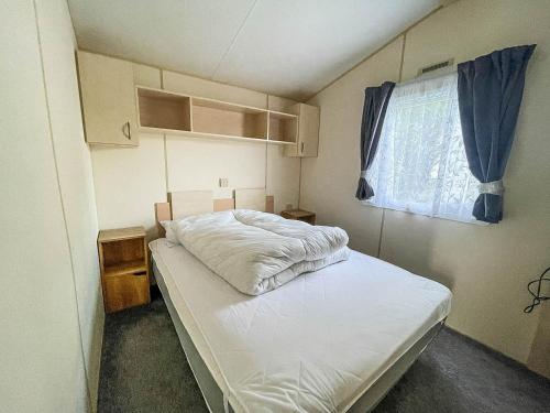 a small bedroom with a bed and a window at Lovely Caravan At Valley Farm Holiday Park, Sleeps 8 Ref 46127v in Great Clacton
