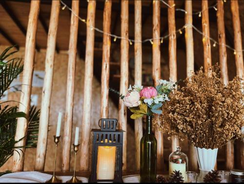 a table with a candle and flowers in a bottle at บ้านหิ่งห้อยผาหมี Baanhinghoi phamee in Mae Sai