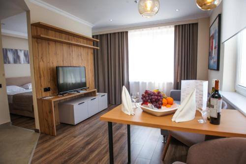 a living room with a table with fruit and a television at Chagala Residence Atyrau in Atyraū