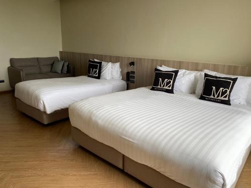 two beds in a room with a couch at M2 Hotel Waterside in Phayao