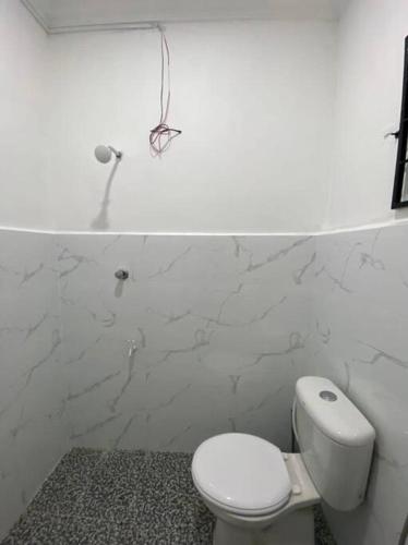 a white bathroom with a toilet and a wall at Lisa Homestay Sandakan in Sandakan