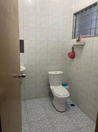 a bathroom with a white toilet and a window at Lisa Homestay Sandakan in Sandakan
