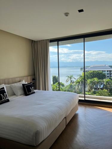 a bedroom with a large bed and a large window at M2 Hotel Waterside in Phayao