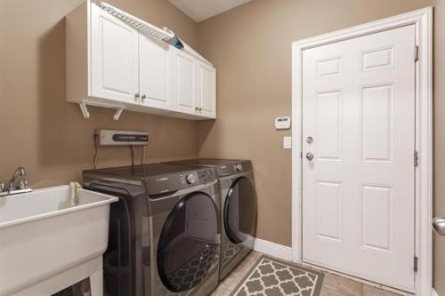 a laundry room with a washing machine and a sink at Green Leaf B&B in West Kelowna