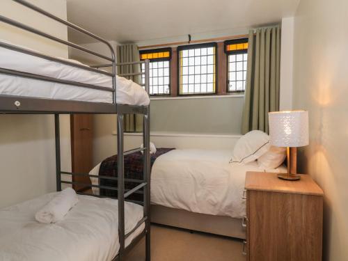 1 Schlafzimmer mit 2 Etagenbetten und einem Tisch mit einer Lampe in der Unterkunft 5 St Mary's Church in Moffat