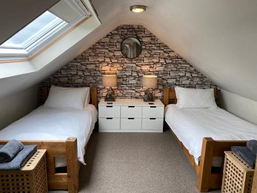 2 Betten in einem Dachzimmer mit einer Steinmauer in der Unterkunft Netherraw in Newcastleton